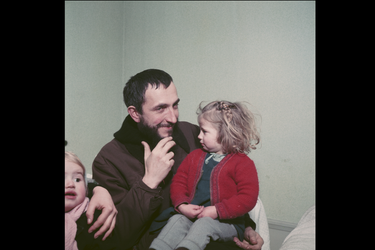 Février 1954 : en visite chez la famille Porte, l'abbé Pierre jouant avec les enfants, la petite Annie blottie contre lui. 