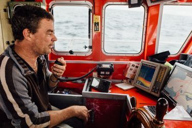 Maxime Vigot, 46 ans, le patron du bateau, discute avec ses amis qui travaillent sur la même zone. La carte sur son ordinateur a gardé en mémoire ses trajectoires de pêche des années précédentes.