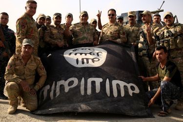 Les soldats irakiens fêtent la prise aux mains de l'Etat islamique de la localité d'al-Shura en montrant notamment le drapeau récupéré à l'EI.