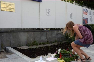 Une femme dépose des fleurs devant l'ambassade de France à Moscou