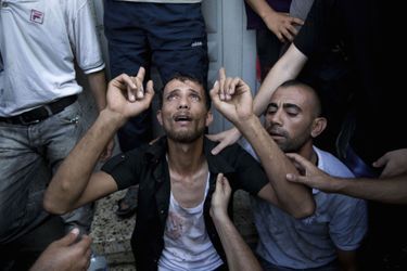Un père palestinien à la morgue de l'hôpital Shifa après que son fils a péri dans une explosion qui a tué huit enfants et deux adultes, et  a blessé 40 personnes dans un jardin public de la ville de Gaza lundi. Israël a nié toute responsabilité, affirmant qu'il s'agissait d'un tir de roquette du Hamas raté. 