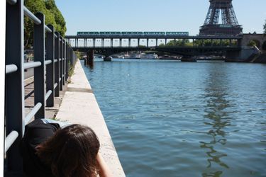 Une femme, allongée sur les quais du Pont de Bir-Hakeim regardant passer le métro aérien et la Tour Eiffel en arrière-plan