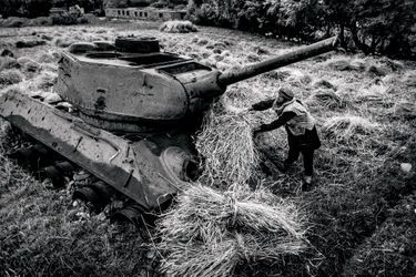 A farmer puts his harvest on a tank left behind in war. The effect of 30 years of war is visible throughout most of the country, and the people have gotten used to living with these ruins.