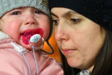 Une mère tient son enfant en larmes, après être arrivée en Pologne pour fuir la guerre en Ukraine.