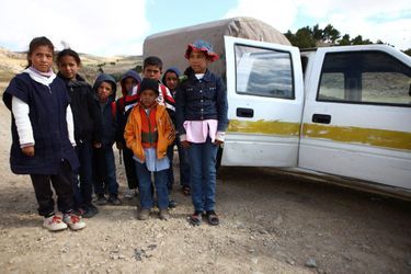 Amal, 11 ans (à dr.), ses petits frères, cousins et cousines devant la voiture qui leur permet d’aller à l’école. Son chauffeur, Khaled, est payé par la fondation Almadanya.