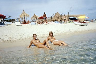Saint-Tropez - août 1970 - Sur la plage de la Voile Rouge à Pampelonne, allongées sur le rivage, deux femmes aux seins nus baignant leurs pieds dans l&#039;eau