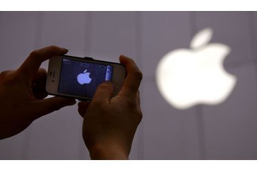 <br />
Un homme photographie un logo Apple avec son iPhone.