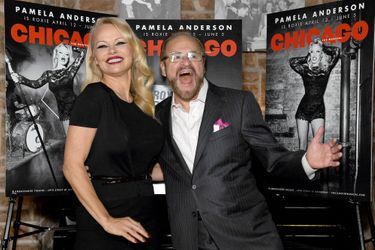 Pamela Anderson et le producteur Barry Weissler posent devant les posters de «Chicago», à New York, le 23 mars 2022.