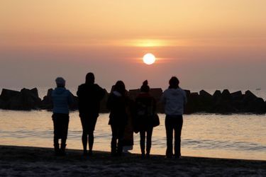 Quatre personnes prient sur la plage d&#039;Arahama, le 11 mars 2022.