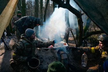 Des membres des forces ukrainiennes se préparent à manger près de Demydiv, le 10 mars 2022.