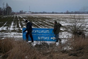 Des membres des forces ukrainiennes retirent un panneau de circulation pour empêcher les soldats russes de se repérer dans la région de Kiev, le 8 mars 2022.