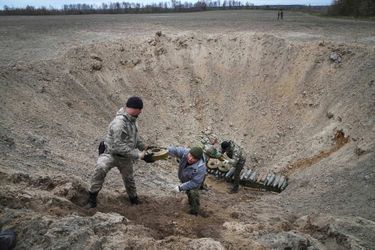 Des soldats ukrainiens placent des mines ramassées dans un cratère pour les faire exploser à Moschchun, près de Kiev, le 19 avril 2022.