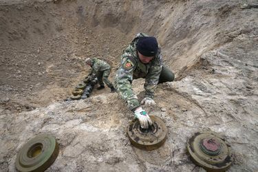 Des soldats ukrainiens placent des mines ramassées dans un cratère pour les faire exploser à Moschchun, près de Kiev, le 19 avril 2022.
