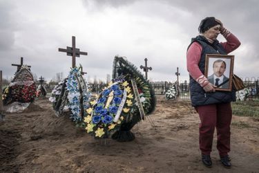 A Boutcha, théâtre d&#039;un massacre commis par l&#039;armée russe, la population enterre ses morts le 21 avril. A droite, une femme tient le portrait de son mari défunt. 