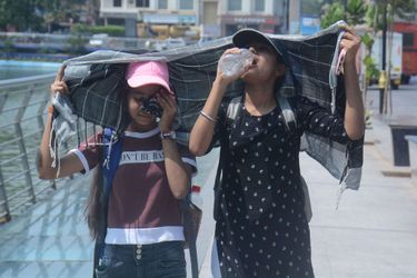 A Bombay, en Inde, deux jeunes filles se couvrent la tête tout en buvant de l&#039;eau sous la chaleur, le 25 avril.