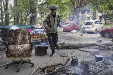 Un homme cuisine dans la rue chez lui près de Marioupol, le 4 mai 2022.