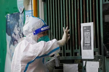 Une personne en tenue de protection effectue un test sur un habitant confiné à Shanghai, en Chine, le 5 mai 2022.