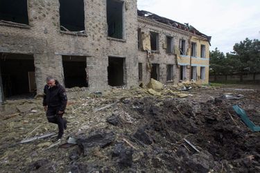 Un policier marche à côté d&#039;un bâtiment scolaire endommagé par une frappe militaire russe, à Kostiantynivka, dans la région de Donetsk, le 22 mai 2022.