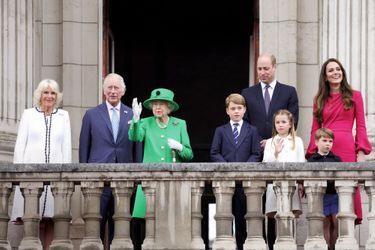 Au balcon de Buckingham, le 5 juin, avec, à la main, une canne ayant appartenu à Philip et, autour d’elle, trois possibles futurs rois, Charles, William et George, avec Camilla, Charlotte, Louis et Kate. 