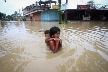 Une petite fille porte son frère dans les rues inondées d&#039;Agartala, en Inde, le 18 juin 2022. 