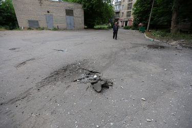 Un résident local marche près des cratères d'obus à la suite de récents bombardements à Donetsk, Ukraine le 23 juin 2022.