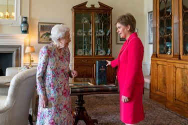 La reine Elizabeth II avec la Première ministre d'Ecosse Nicola Sturgeon qui lui a apporté une bouteille de whisky, à Edimbourg le 29 juin 2022