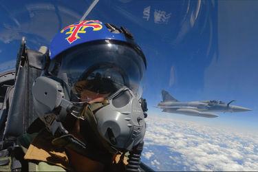 Sur le casque du capitaine Alexandre, dit «Al », une fleur de lys et la croix de Lorraine, symboles de l’escadron 2/5 Île-de-France. Derrière, un Mirage 2000C avec sous ses ailes des réservoirs additionnels de kérosène. 