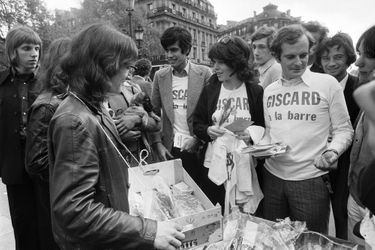 Le fils du candidat à l'élection présidentielle française de 1974 Valery Giscard d'Estaing, Henri Giscard d'Estaing et la chanteuse Dani distribuent des t-shirts de campagne portant l'inscription "Giscard à la barre", le 1er mai 1974, place de l'Opéra à Paris, à quelques jours du premier tour de l'élection présidentielle française de 1974.