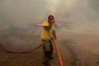 Un habitant de Vatera, sur l'île de Lesbos, tente d'éteindre les flammes.