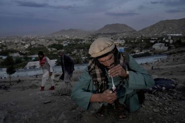 Un toxicomane fume de l’héroïne dans un faubourg de Kaboul, le 9 juin. 