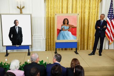 Barack Obama pose à côté des portraits de son épouse de lui.