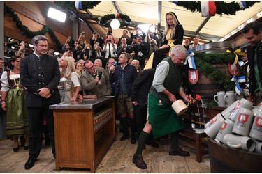 Comme le veut la tradition, le maire de Munich, Dieter Reiter, à droite, a donné le coup d'envoi des festivités en perçant à coup de marteau le premier fût de bière, offrant la première chope au chef de l'Etat régional de Bavière, Markus Söder, debout à gauche.