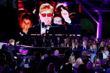 "Quel taudis ici!", a plaisanté Sir Elton John, costume noir scintillant et lunettes aux verres orangés, en se mettant au piano. Derrière lui, la résidence du président américain tout illuminée, et une fanfare militaire en grande tenue.