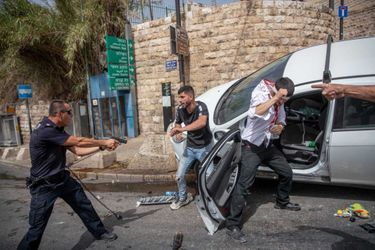 Second de la catégorie "Documentaire et photojournalisme" : Ohad Zwigenberg. Un policier israélien se tient avec son pistolet pointé sur un Palestinien. À côté d'eux se trouve un chauffeur juif qui a été attaqué par des manifestants palestiniens. 