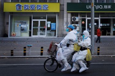 Deux personnes en tenue de protection dans les rues de Pékin.
