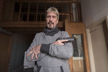 John McAfee poses with a gun in his hand in 2015.