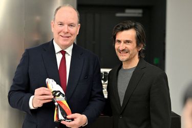 Le pilote Stéphane Ortelli remet au prince Albert de Monaco une paire de gant créé par Mick Schumacher pour la fondation de son père Michael Schumacher lors de l'inauguration de l'exposition de voitures de sport Porsche, au sein de la Collection de Voitures du Prince de Monaco, le 24 février 2023.