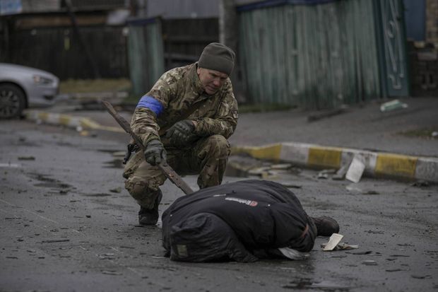 Un soldat ukrainien inspecte un corps, pour s'assurer qu'une mine n'y a pas été placée, à Boutcha, le 2 avril 2022.