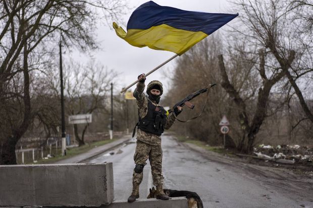 Un soldat ukrainien brandit un drapeau national à un check-point à Boutcha, le 2 avril 2022.