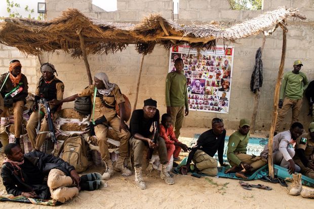 Devant la maison de leur chef Maidroma, à Maiduguri, à quelques kilomètres des bastions de Boko Haram, le 7 mars. Sur l’affiche, les visages des terroristes recherchés, dont Abubakar Shekau, leader de la secte djihadiste. Devant la maison de leur chef Maidroma, à Maiduguri, à quelques kilomètres des bastions de Boko Haram, le 7 mars. Sur l’affiche, les visages des terroristes recherchés, dont Abubakar Shekau, leader de la secte djihadiste.