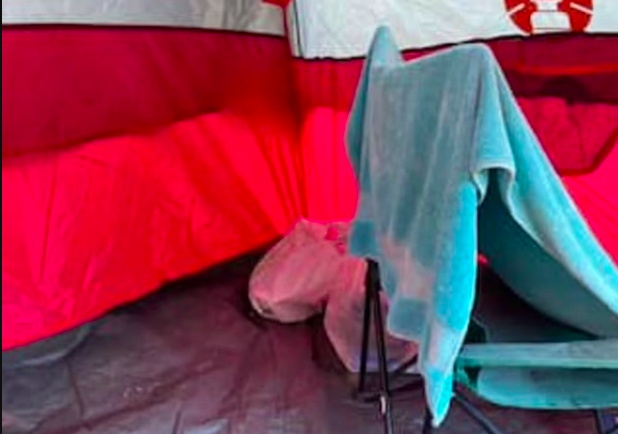 L'intérieur de la tente : une chaise pliante, des serviettes, quelques sacs plastiques...