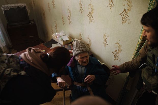 Les volontaires Philip et Masha tentent de convaincre une dame âgée de les suivre. À cause d’un bombardement, elle n’a plus de vitres à ses fenêtres.