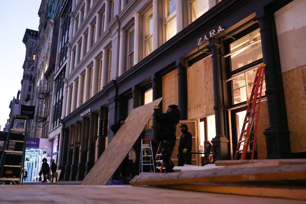 A New York, des salariés installent des protections devant un magasin, à la veille de l'élection présidentielle, lundi soir.