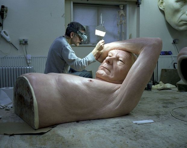 Ron Mueck dans son atelier travaillant le grain de peau de la main de la sculpture.