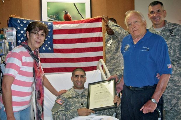 Avec ses parents et le colonel qui lui a remis le décret encadré officialisant sa promotion au grade de capitaine, en septembre 2012.