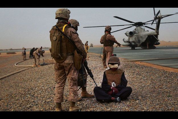  Sur la base aérienne de Dwyer, deux marines surveillent un prisonnier taliban qu’ils accompagnent pour un interrogatoire. 