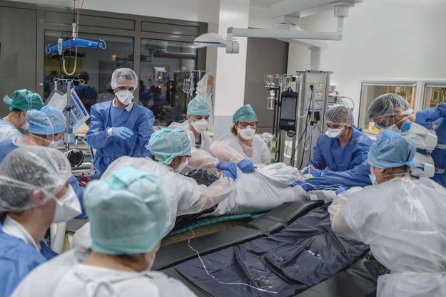 Les urgentistes (en bleu) et l’équipe de réanimation (en blanc) font passer le malade du brancard à un lit. Au CHU de Toulouse, en réa polyvalente de Rangueil, le 22 décembre.