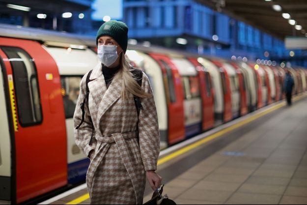 Une femme portant un masque marche à la gare de Londres.