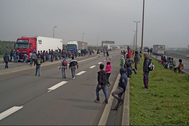 Des migrants à l’assaut des camions sur l’autoroute qui mène au port de Calais, mercredi 17 septembre. Certains bloquent les poids lourds et retournent leur rétroviseur pour empêcher les chauffeurs de voir ce qui se passe à l’arrière.