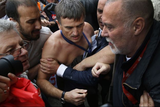 Le DRH, torse nu, tentant d'échapper aux manifestants. 